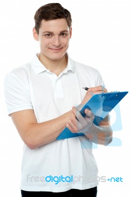 Young Man Writing On Clipboard Stock Photo