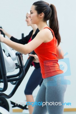 Young People With Elliptic Machine In The Gym Stock Photo