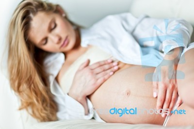 Young Pregnant Woman Resting On Sofa Stock Photo