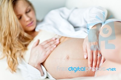 Young Pregnant Woman Resting On Sofa Stock Photo