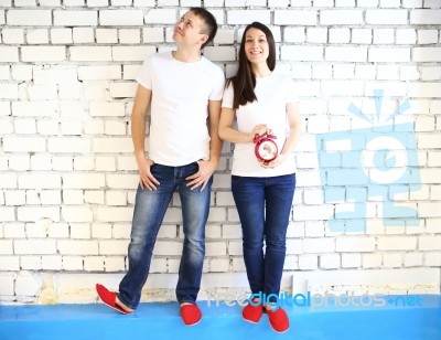 Young Smiling Couple With Red Alarm Clock Stock Photo