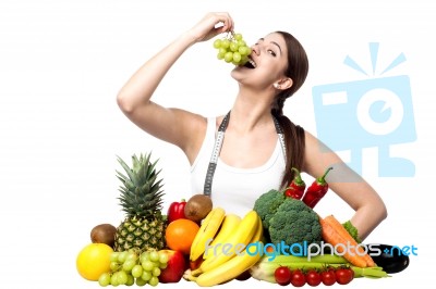 Young Smiling Girl Eating Grapes, Looking At Camera Stock Photo