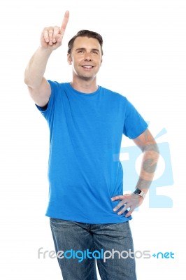 Young Smiling Male Pointing Up The Copy Space Stock Photo