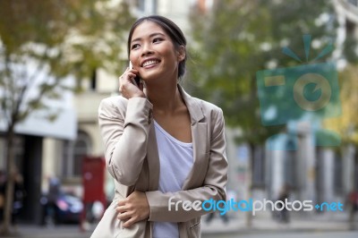 Young Woman And Smart Phone Walking On Street Stock Photo