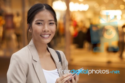 Young Woman And Smart Phone Walking On Street Stock Photo