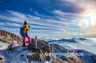 Young Woman Hiker Taking Photo With Smartphone On Mountains Peak In Winter Stock Photo