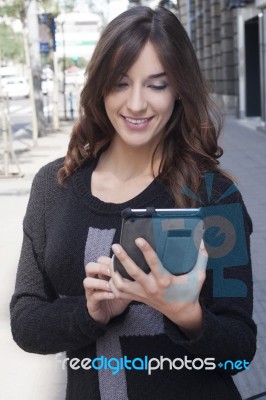 Young Woman Holding A Tablet On The Street Stock Photo