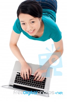 Young Woman Lying On Floor Using Laptop Stock Photo