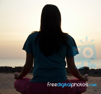 Young Woman Meditating On Beach Stock Photo