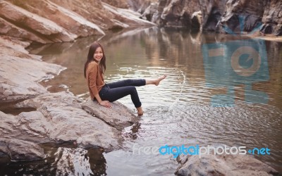 Young Woman On A River Bank Playing With Water Stock Photo