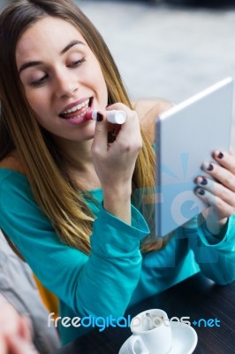 Young Woman Painting Her Lips With A Digital Tablet In A Coffee Stock Photo