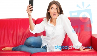 Young Woman Posing While Taking Selfie On Sofa Stock Photo