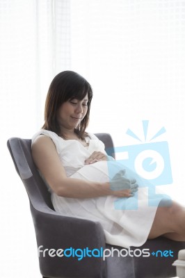 Young Woman Pregnant Sitting On Arm Chairs In Home Living Room W… Stock Photo