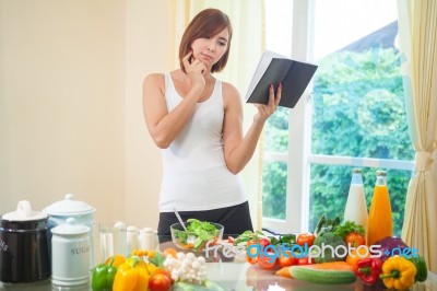 Young Woman Reads Cookbook Stock Photo