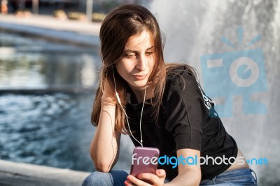 Young Woman Sitting  And Listening To Her  Music Stock Photo