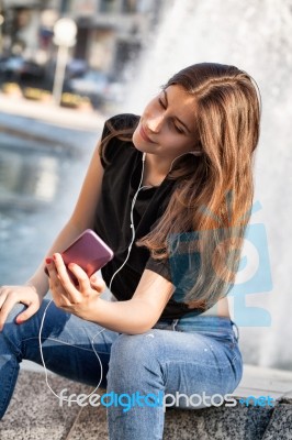 Young Woman Sitting  And Listening To Her  Music Stock Photo