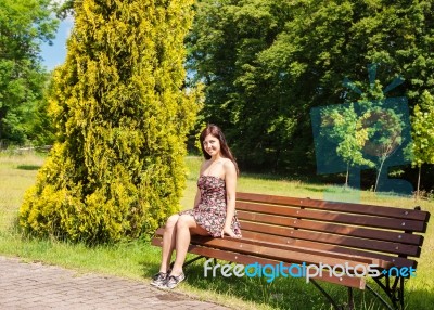 Young Woman Sitting On A Park Bench Stock Photo