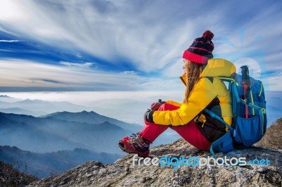 Young Woman Sitting On The Hill Of High Mountains Stock Photo