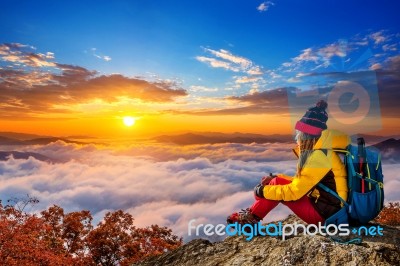 Young Woman Sitting On The Hill Of High Mountains At Sunrise Stock Photo