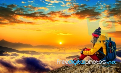 Young Woman Sitting On The Hill Of High Mountains At Sunrise Stock Photo