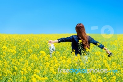 Young Woman Standing In Yellow Rapeseed Field Stock Photo