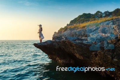 Young Woman Standing On The Top Of Rock And Looking At The Seashore And Sunset In Si Chang Island Stock Photo