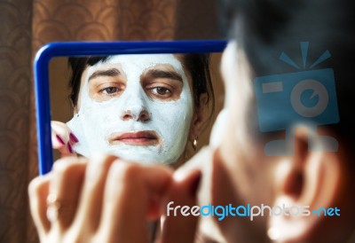 Young Woman Takes Beauty Mask In Front Of Mirror Stock Photo