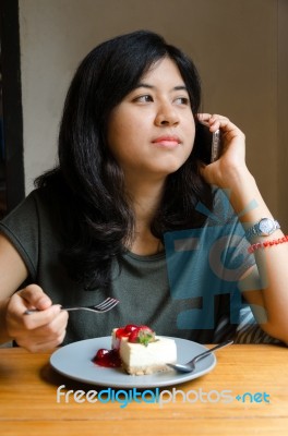 Young Woman Talking Mobile Phone With A Cake In Cafe Stock Photo