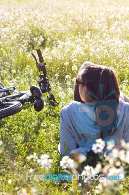 Young Woman With Mountain Bike Stretched On The Field Stock Photo