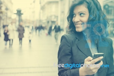 Young Woman With Smartphone Walking On Street Stock Photo