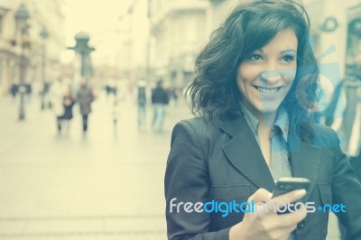 Young Woman With Smile And Smartphone Walking On Street Stock Photo