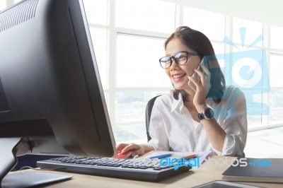 Young Working Woman Talking To Phone With Watching On Computer On Office Table Use For Business Connecting ,customer Service ,communication Stock Photo