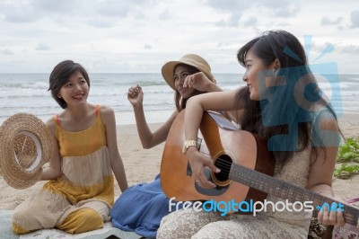 Younger Asian Woman Friend Vacation Relaxing Playing Guitar And Sing A Song On Sea Beach Stock Photo