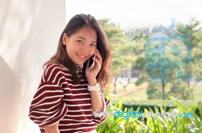 Younger Asian Woman Talking On Smart Phone With Happiness Emtion… Stock Photo