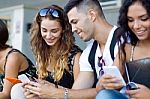 A Group Of Students Having Fun With Smartphones After Class Stock Photo