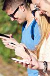 A Group Of Students Having Fun With Smartphones After Class Stock Photo