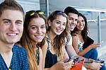 A Group Of Students Having Fun With Smartphones After Class Stock Photo