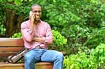 African Man Sitting On A Bench, Talking On Phone Stock Photo