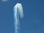 Aircrafts Drawing White Smoke Circles Into The Blue Sky Stock Photo