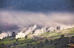 Alpine Village In Mountains. Smoke, Bonfire And Haze Over Hills Stock Photo