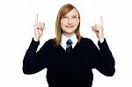 Amused Schoolgirl Looking And Pointing Upwards Stock Photo