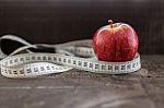 An Apple Surrounded By A Measuring Tape Tailor On Wood Stock Photo