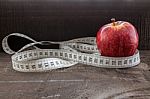 An Apple Surrounded By A Measuring Tape Tailor On Wood Stock Photo