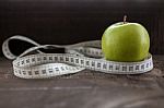 An Apple Surrounded By A Measuring Tape Tailor On Wood Stock Photo