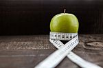 An Apple Surrounded By A Measuring Tape Tailor On Wood Stock Photo