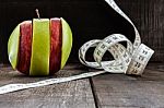 An Apple Surrounded By A Measuring Tape Tailor On Wood Stock Photo