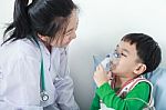 Asian Boy Having Respiratory Illness Helped By Health Professional With Inhaler Stock Photo