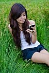 Asian Cute Girl Texting On Meadow Stock Photo