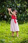 Asian Girl Catches Soap Bubbles On Nature Background. Outdoors Stock Photo