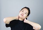 Asian Girl In Black Casual Dress Catch That Shoulder, Because Of The Pain Of Hard Work. Or Something Hit The Shoulder. On A Gray Background Gives A Soft Light Stock Photo